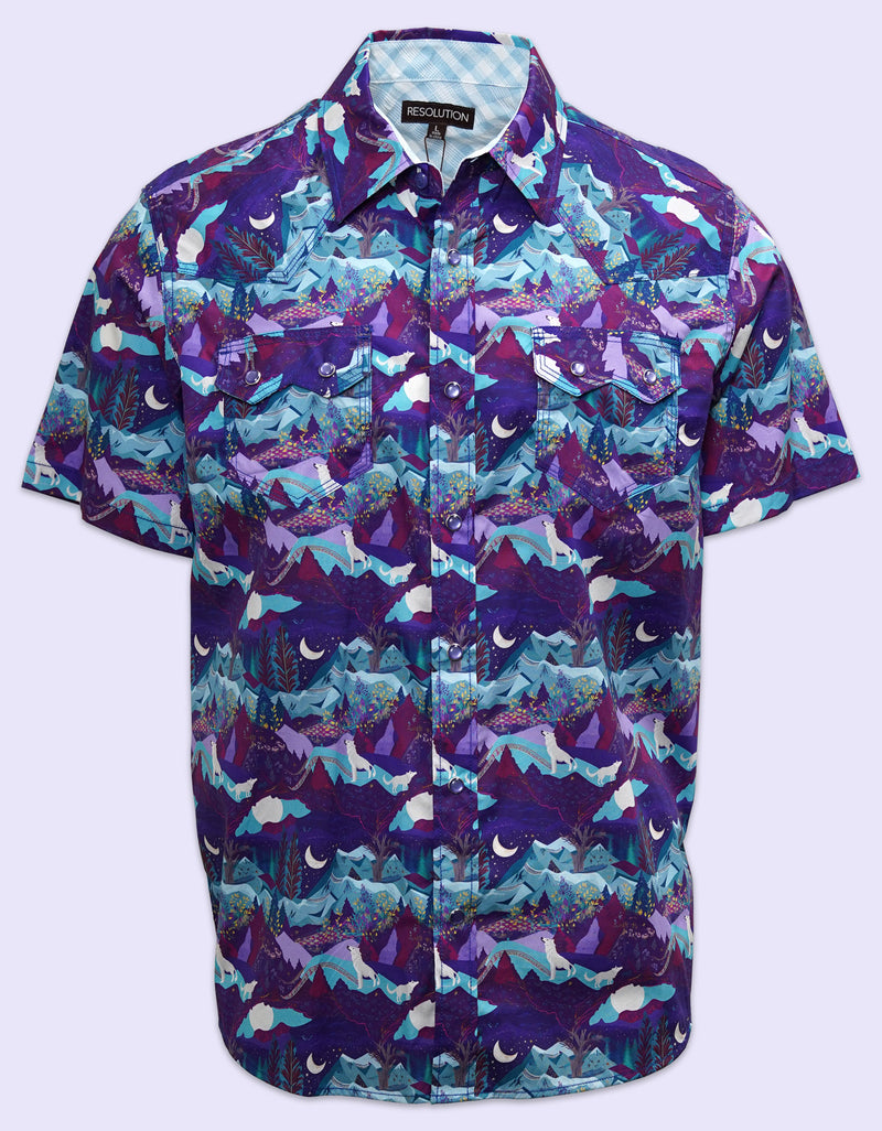 A short-sleeve button-down shirt showcasing a vibrant geometric pattern with abstract jagged mountain shapes in purple, blue, teal, and magenta tones against a white background.