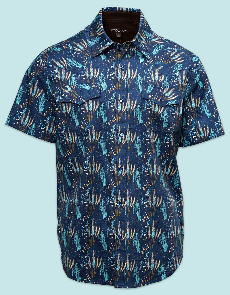 A navy blue short-sleeve button-down western shirt featuring an all-over desert cactus print in green and orange tones on a light blue background.